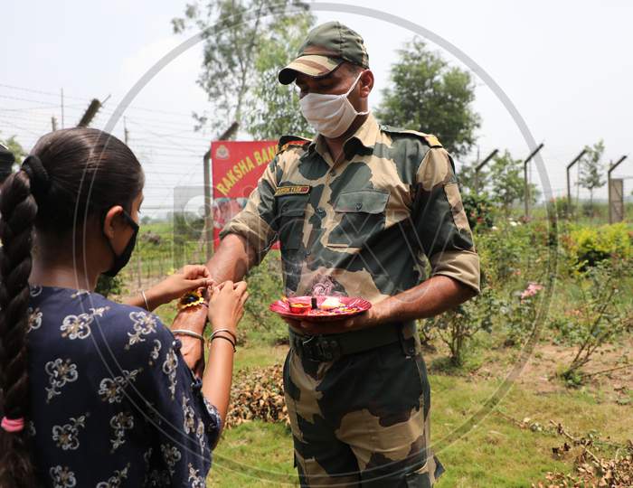 A girl ties a Rakhi on the wrist of Border Security Force (BSF) personnel at the international border Octroi post in Suchetgarh, Jammu, on August 2, 2020.