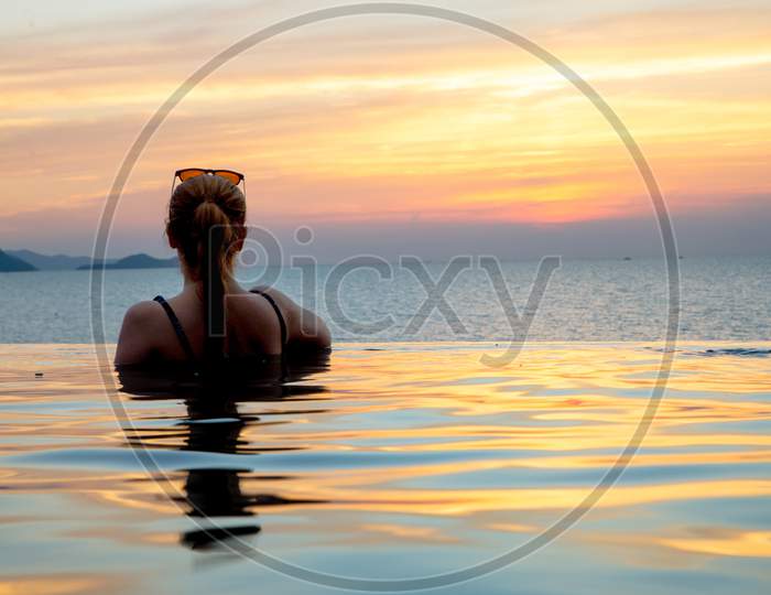 A lady enjoying sunset in infinity pool