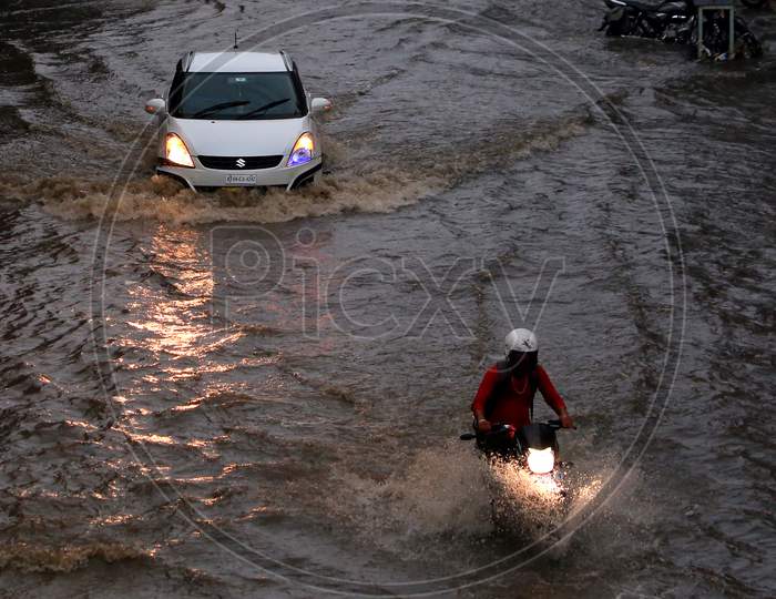 Indian People drive through a flooded road during heavy rains in Ajmer, On August 1, 2020.
