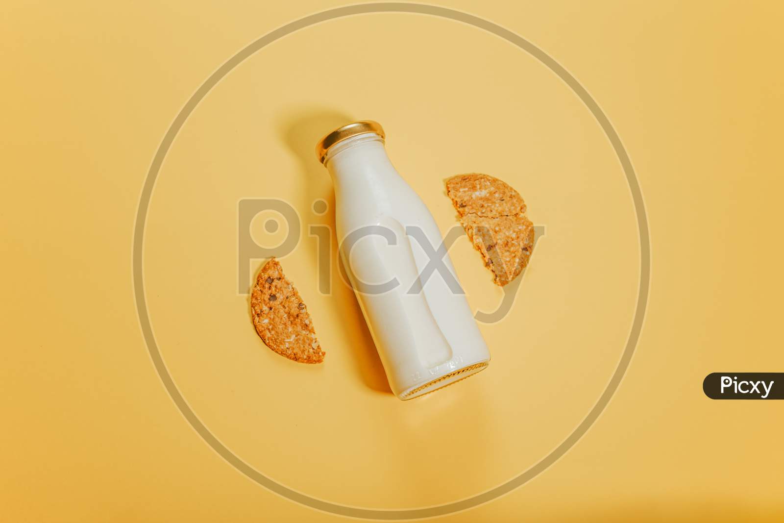 A Bottle Of Milk Surrounded By Two Pieces Of One Cookie