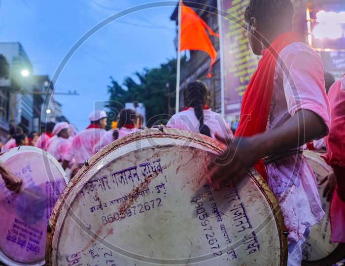 A group of men playing dhol a musical instrument in a religious procession