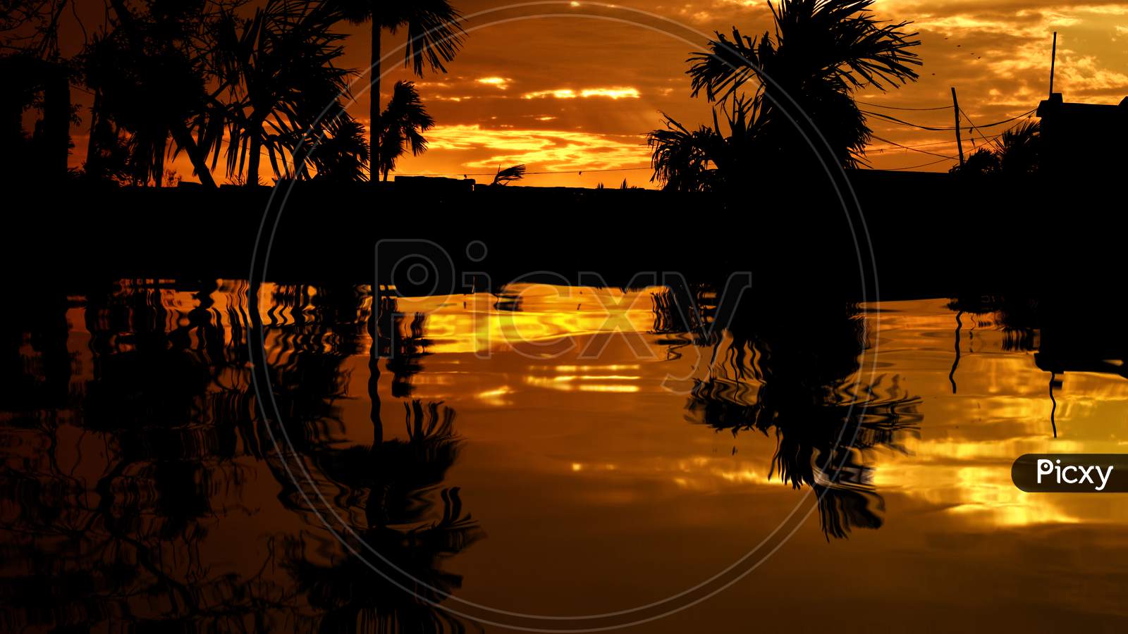 Beautiful Landscape of Illuminated Colorful Sky at Sunset, Reflection on Lake Water After Rain in Afternoon. All Are Black in Shadow And Bright Yellow Clouds on The Sky by The Last Sunshine of Day.
