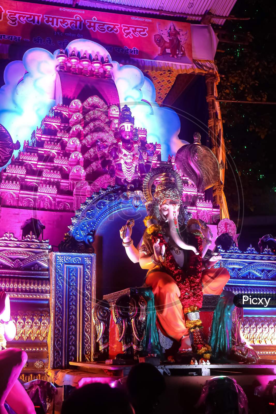 An idol of lord Ganesh beautifully decorated with flowers and lights