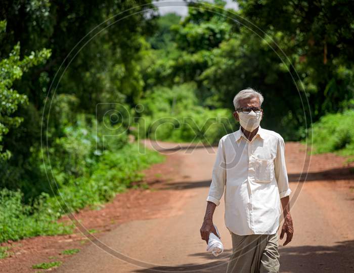 Old man wearing mask  due to covid 19 and walking in a road