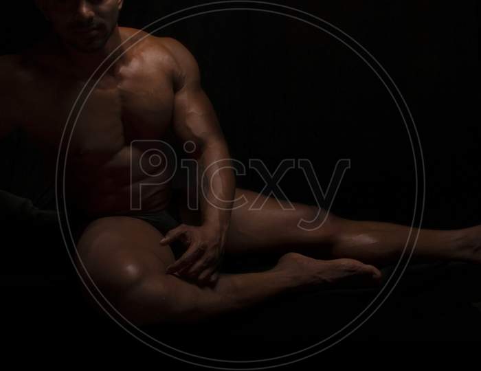 Silhouette of young athlete bodybuilder man on black