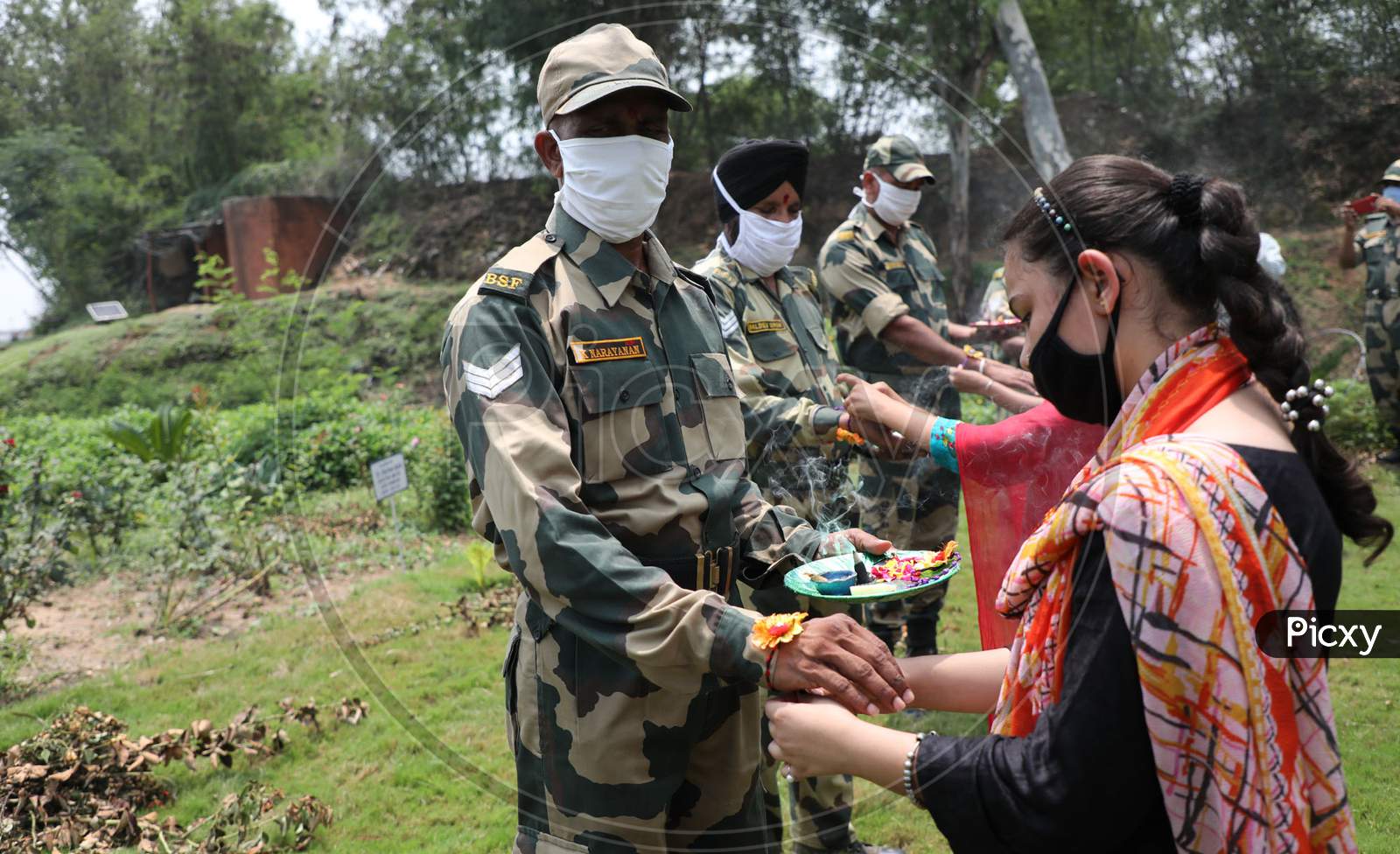 Girls tie Rakhi on the wrists of Border Security Force (BSF) personnel at the international border Octroi post in Suchetgarh, Jammu, on August 2, 2020.