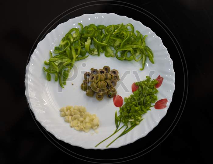 Closeup shot of chopped peppers and olives, airy cheese and herbs on a plate on black background