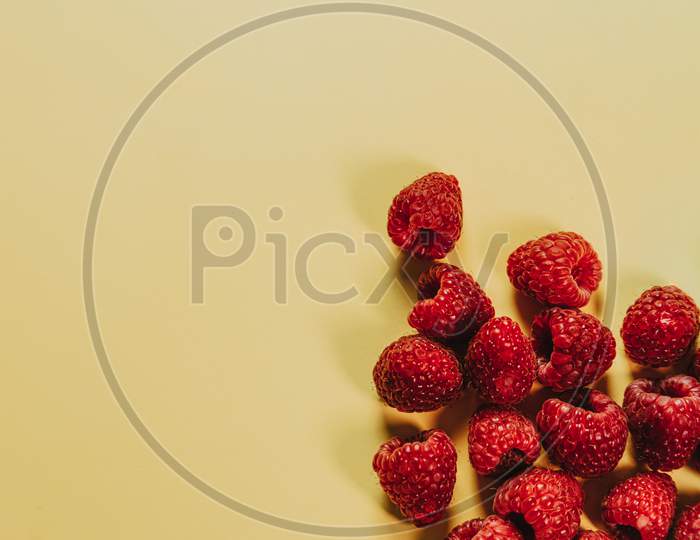 Bunch Of Raspberries Over A Clean Yellow Background