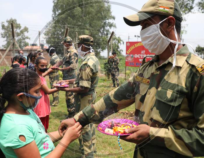 Girls tie Rakhi on the wrists of Border Security Force (BSF) personnel at the international border Octroi post in Suchetgarh, Jammu, on August 2, 2020.