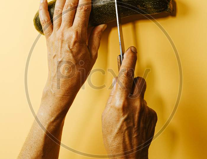 Two Old Woman Hands Cutting A Zucchini