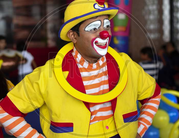 A clown in a pink and yellow suit