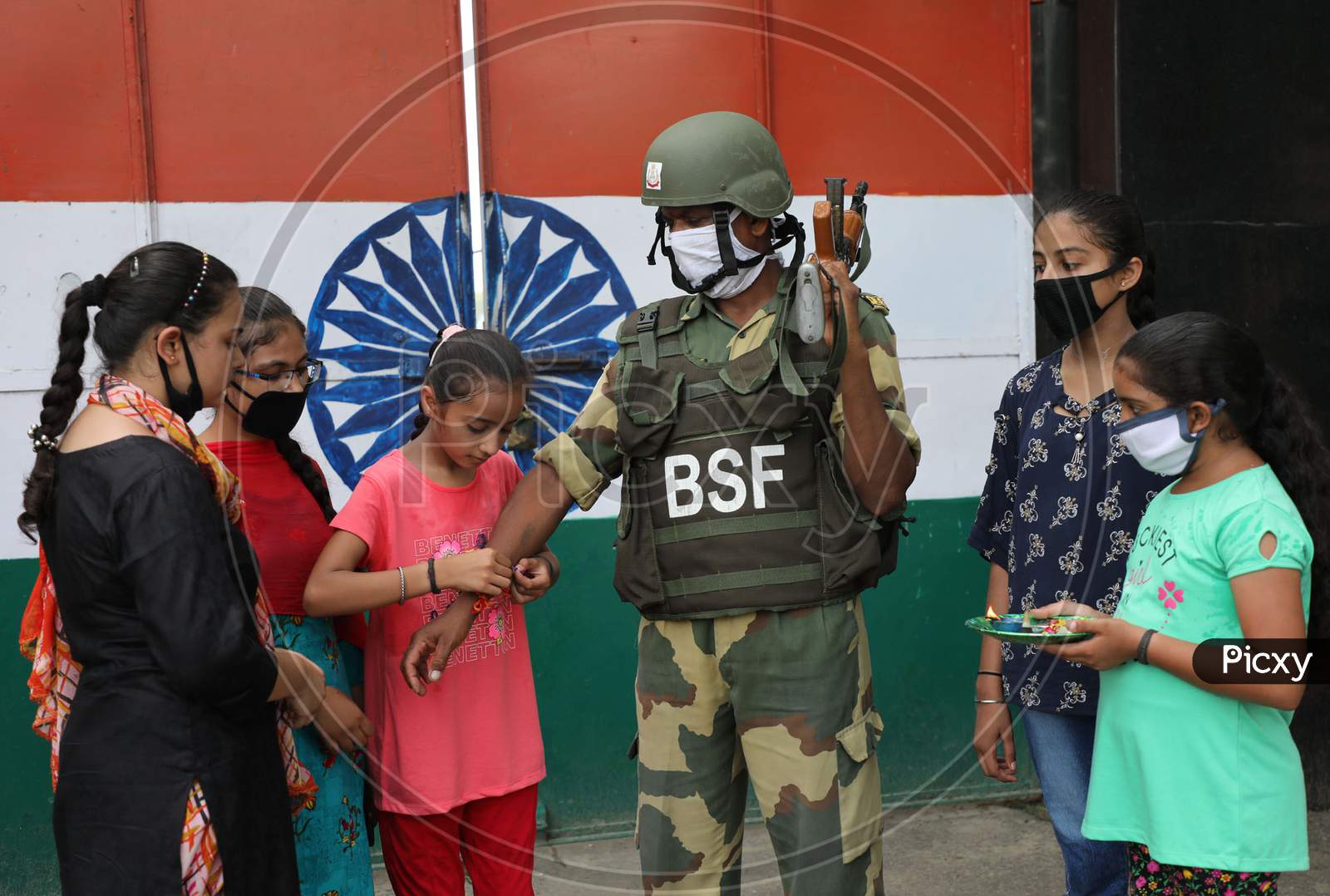 Girls tie Rakhi on the wrist of Border Security Force (BSF) personnel at the international border Octroi post in Suchetgarh, Jammu, on August 2, 2020.