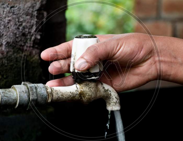 Hand Of A Girl Turning On An Old Plastic Water Tap