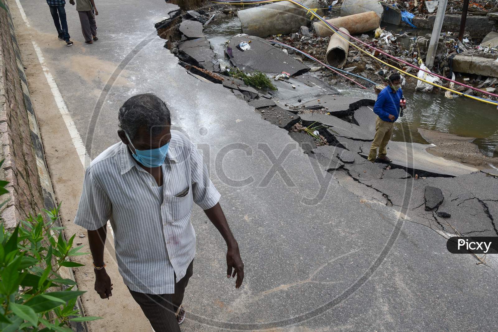People Walk past a road which got shrinked due to floods in Hanamkonda, Warangal, August 18, 2020.
