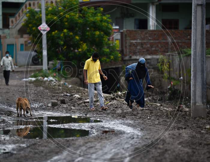 people walk through a road filled with slippery mud after floods in Warangal, august 18, 2020