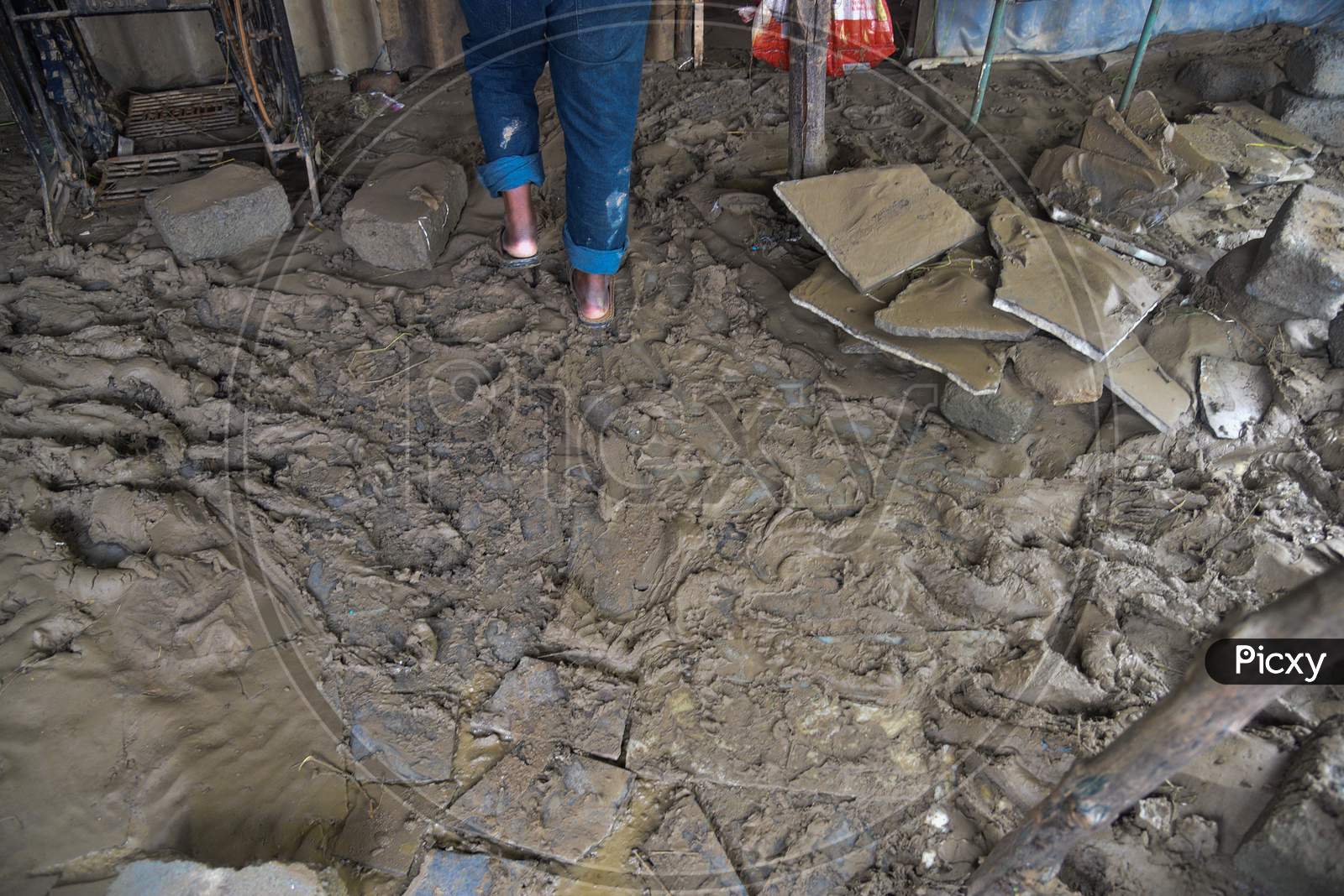 People clean up the mud that accumulated in their home caused by the flash floods in warangal, August 18, 2020.