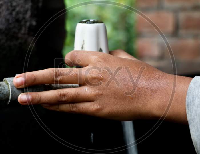 Hand Of A Boy Turning On An Old Plastic Water Tap