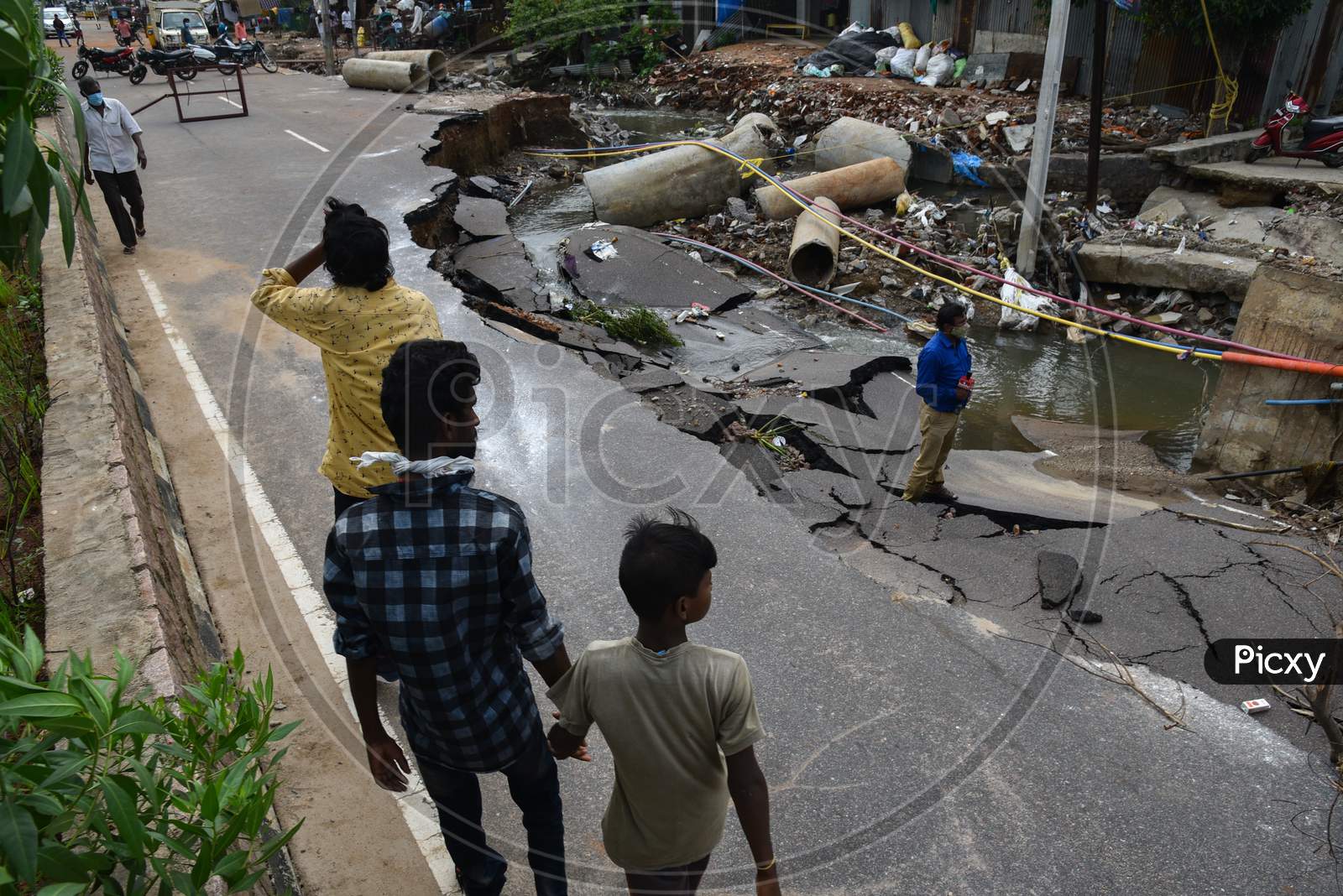 People Walk past a road which got shrinked due to floods in Hanamkonda, Warangal, August 18, 2020.