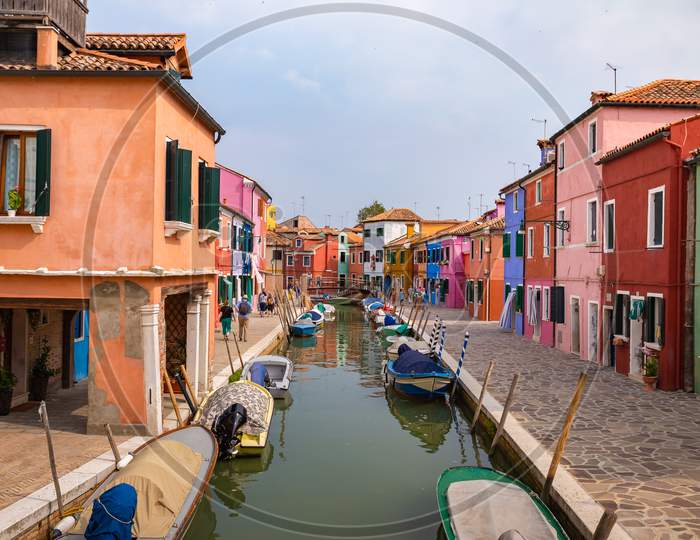 Burano, Italy - 09-18-2019 Colorful Houses By Canal In Burano, Italy. Burano Is An Island In The Venetian Lagoon And Is Known For Its Lace Work And Brightly Colored Homes.