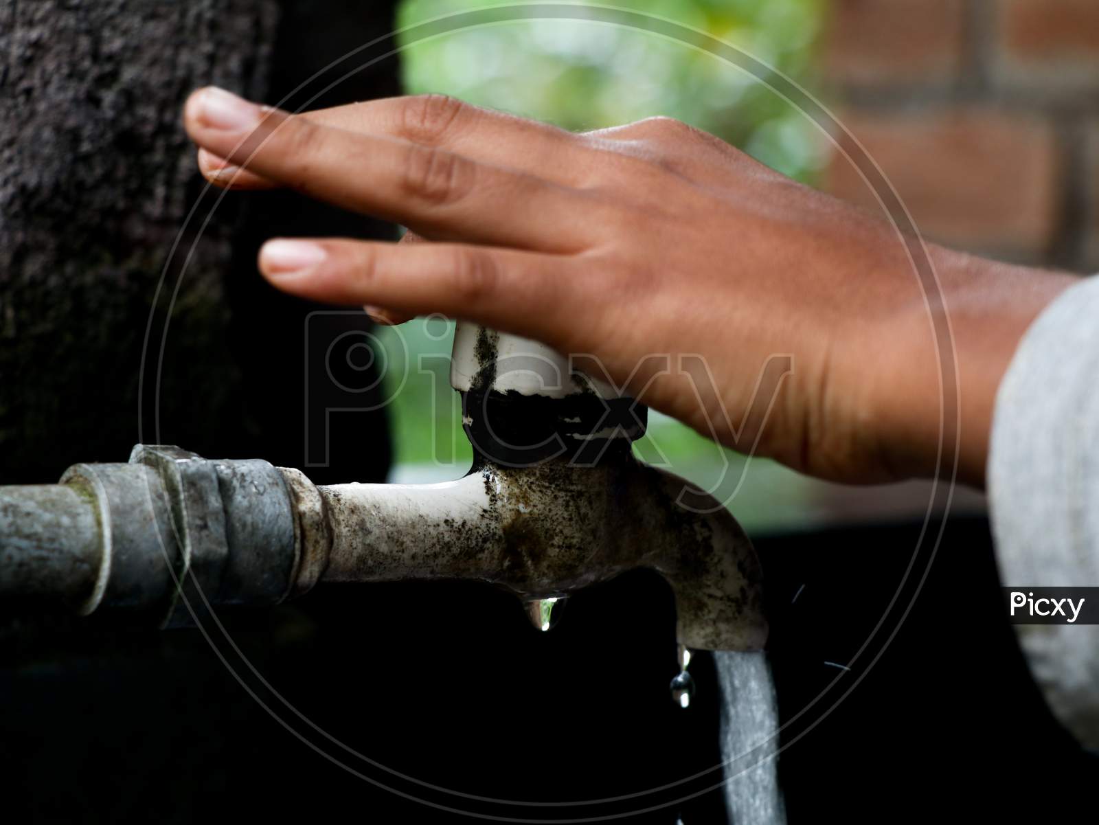 Hand Of A Boy Turning On An Old Plastic Water Tap