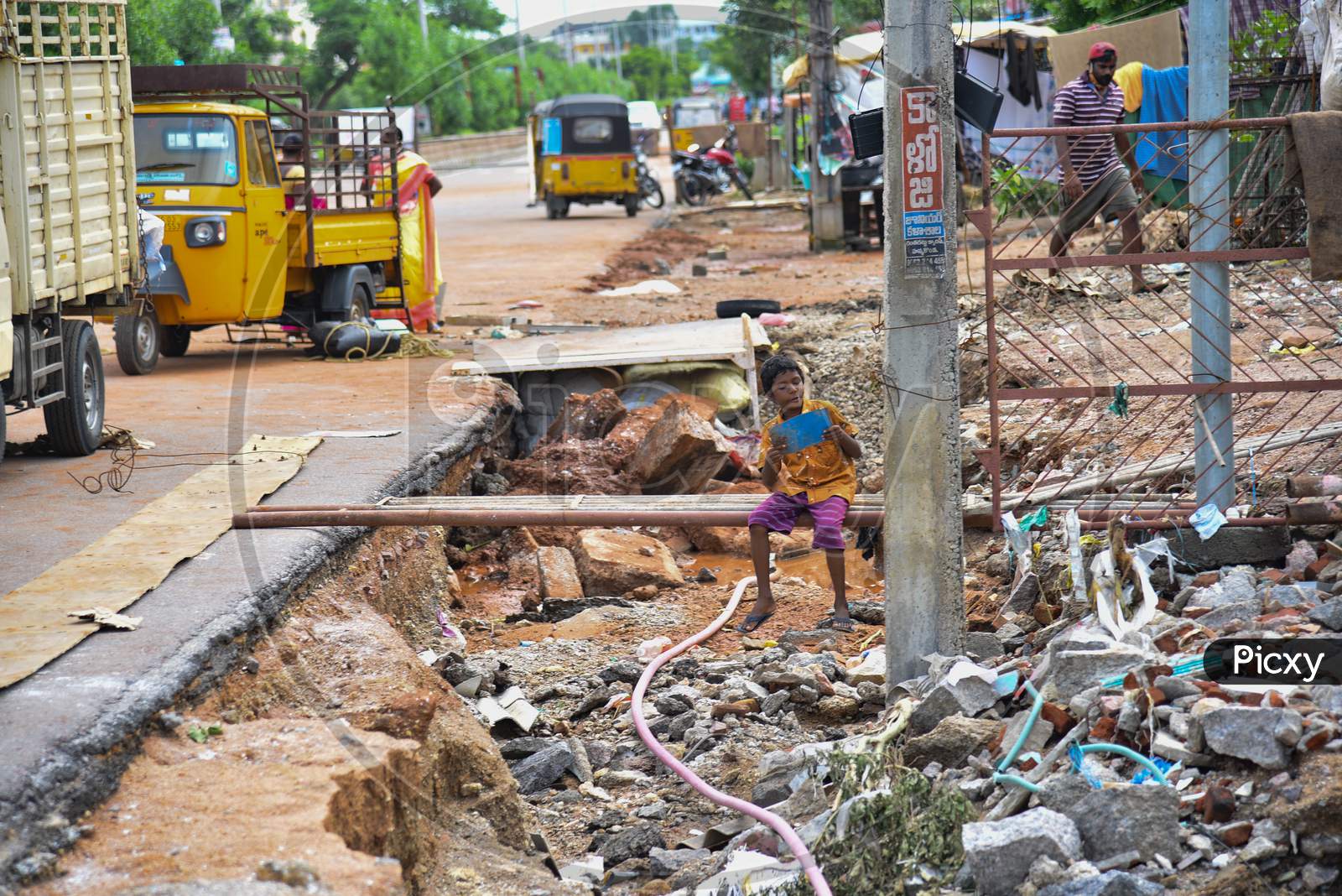 A boy plays with a steel plate at the road shrinking site after flash floods in Hanamkonda, August 18, 2020