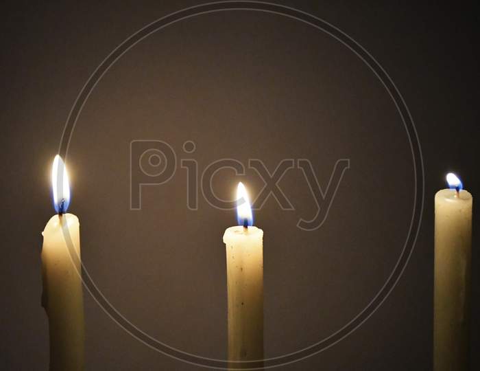 White Candles Burning in the Dark with lights glow, the burning candle's flame in the dark background, a symbol of the Christian faith, Candles burning in the Dark with lights glow