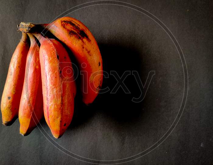 Four Red Bananas Isolated On Black Background. Copy Space