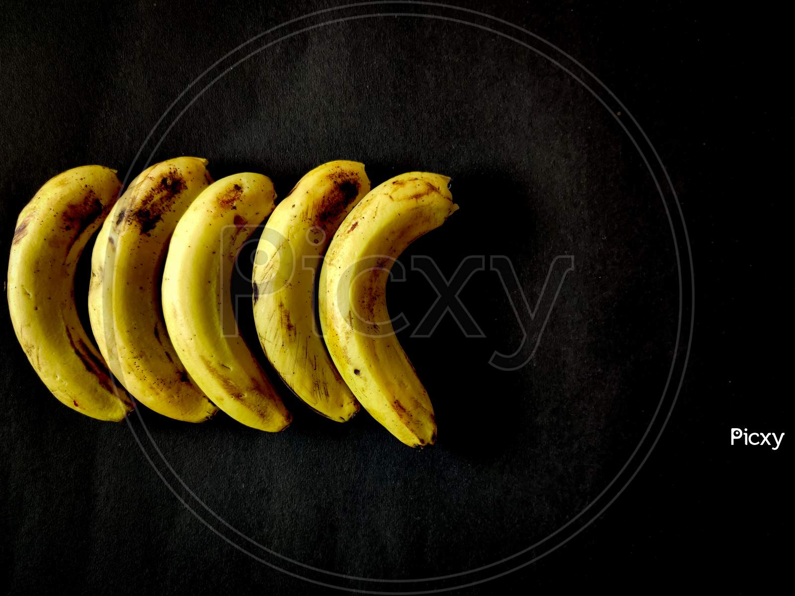 Five Bananas Isolated On Black Background. Copy Space