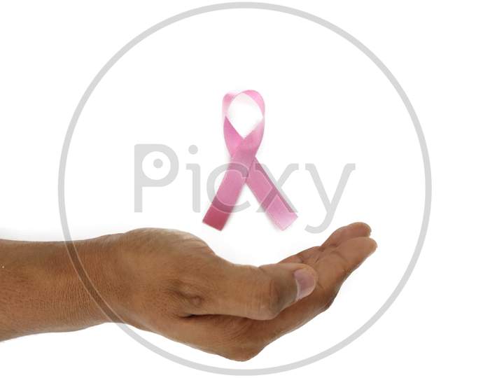 Pink ribbon breast cancer awareness symbol kept between hands as Support and care Concept