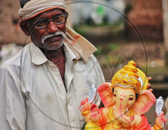 Man Holding Idol Of Lord Ganesha