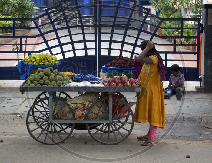 Bangalore, India - September 04, 2016: A Woman Sell Vegetable And Fruit On A Cart Wheel In Front Of An Apartment Entrance Street