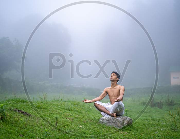 A Man Practicing Meditation And Zen Energy Yoga In Mountains.Man Doing Fitness Exercise Sport Outdoors In Morning. Healthy Lifestyle Concept