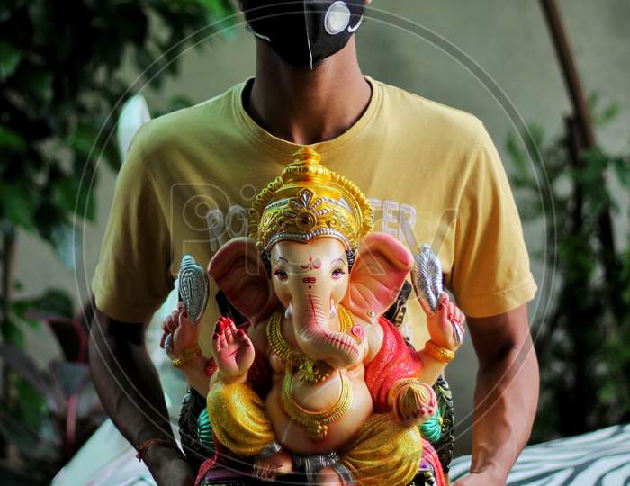 Boy Wearing N 95 Mask Holding Idol Of Lord Ganesha