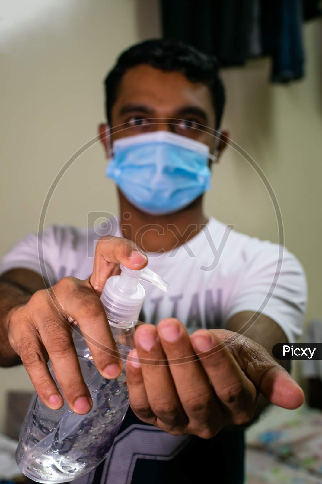 An Indian Man Wearing Mask And Taking Hand Sanitizer To His Hand
