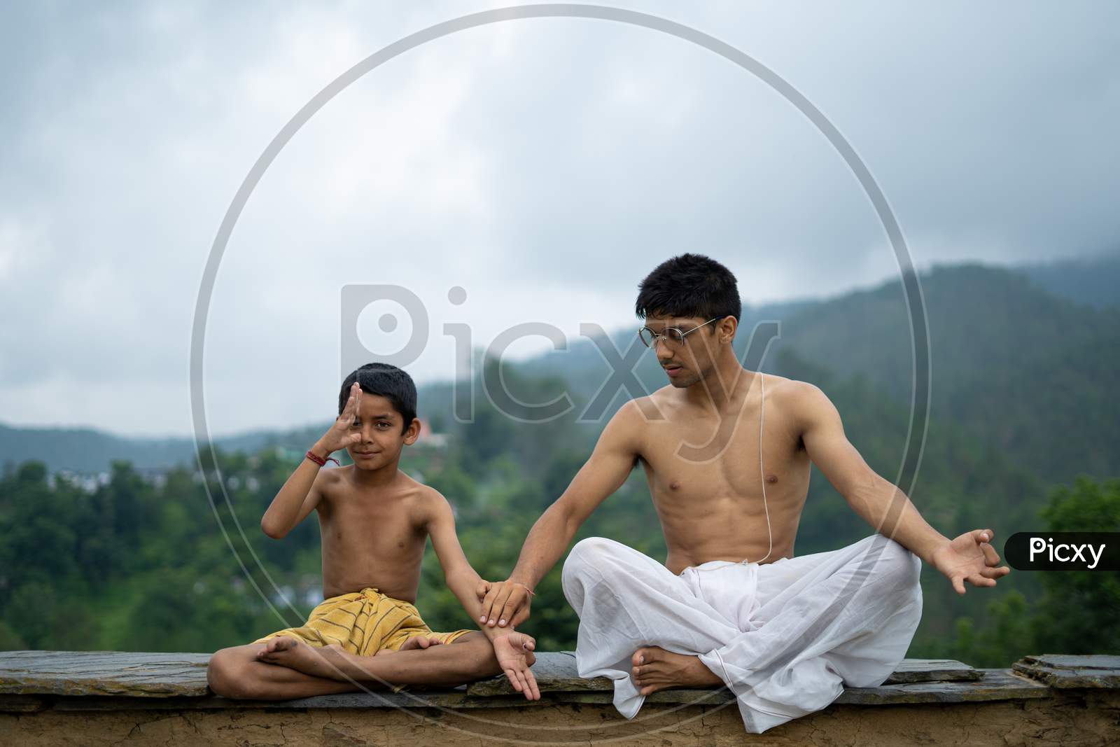 A Teenage Boy And A Kid, Practicing Meditation And Zen Energy Yoga In Mountains. Brothers Doing Fitness Exercise Sport Outdoors In Morning. Healthy Lifestyle Concept
