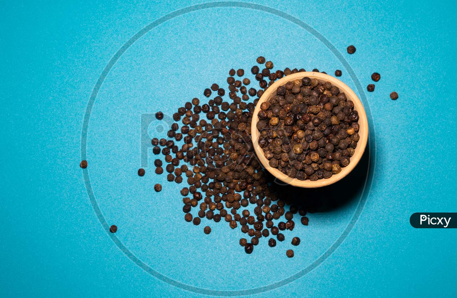 A Bunch Of Black Pepper Spread From A Clay Pot With Blue Background