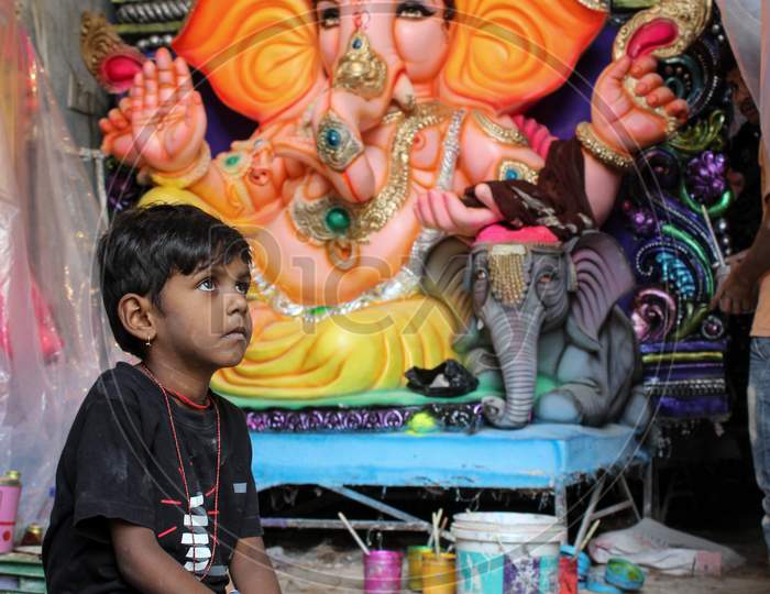 Kid gazing at ganesh idols inside idol making workshop
