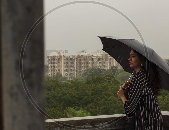 Indian Woman With Umbrella In The Rain. Looking At Camera.