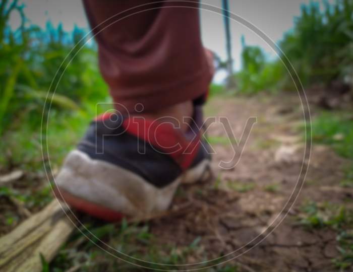 Running sport shoe in feet cramped on dry farm land (blurred)