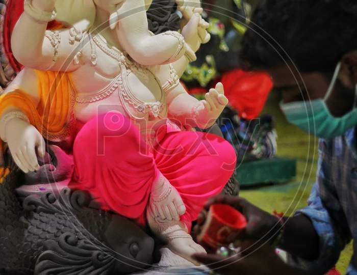 Man Coloring Idol Of Lord Ganesha