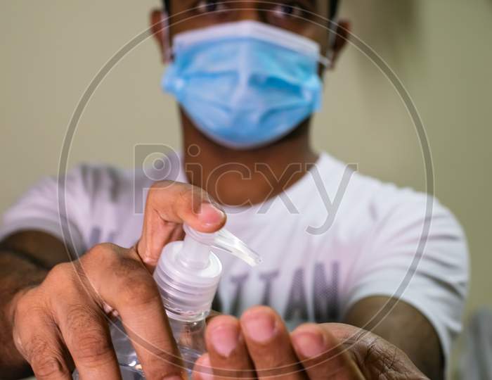 An Indian Man Wearing Mask And Taking Hand Sanitizer To His Hand