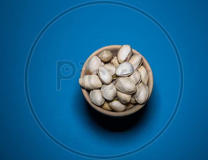 A Bunch Of Pista In A Clay Pot With Blue Background
