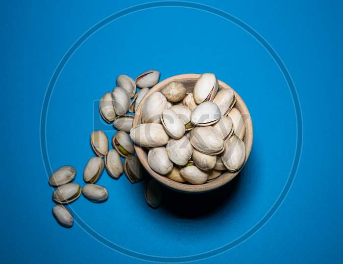 A Bunch Of Pista Spread From A Clay Pot With Blue Background
