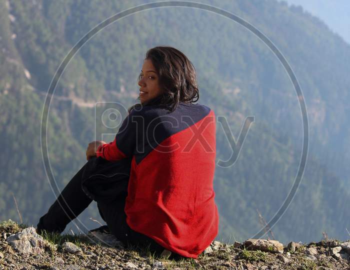 Young Indian Female Sitting On The Edge Of The Mountain