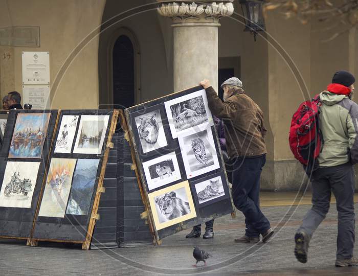 Krakow, Poland - December 16, 2014: A Sketch Painting Artist Stand Next To His Artwork In City Center Main Square During Xmas Holidays