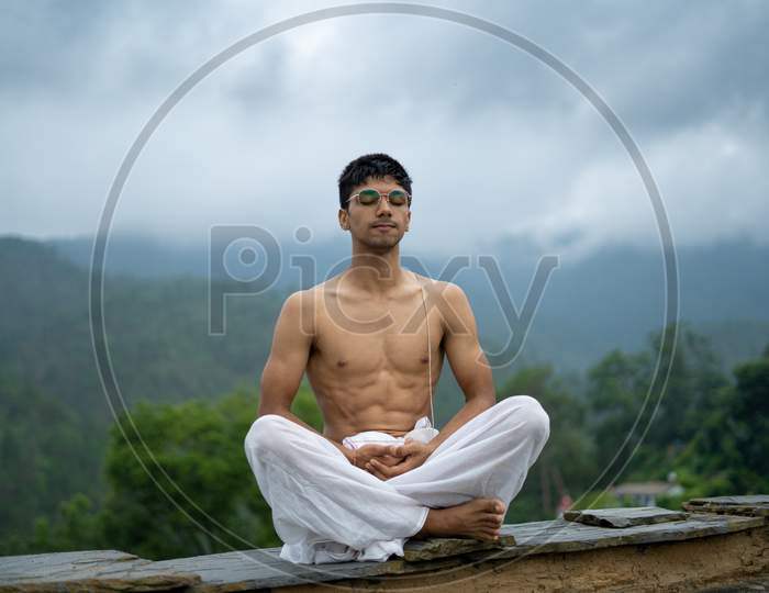 A Man Practicing Meditation And Zen Energy Yoga In Mountains.Man Doing Fitness Exercise Sport Outdoors In Morning. Healthy Lifestyle Concept