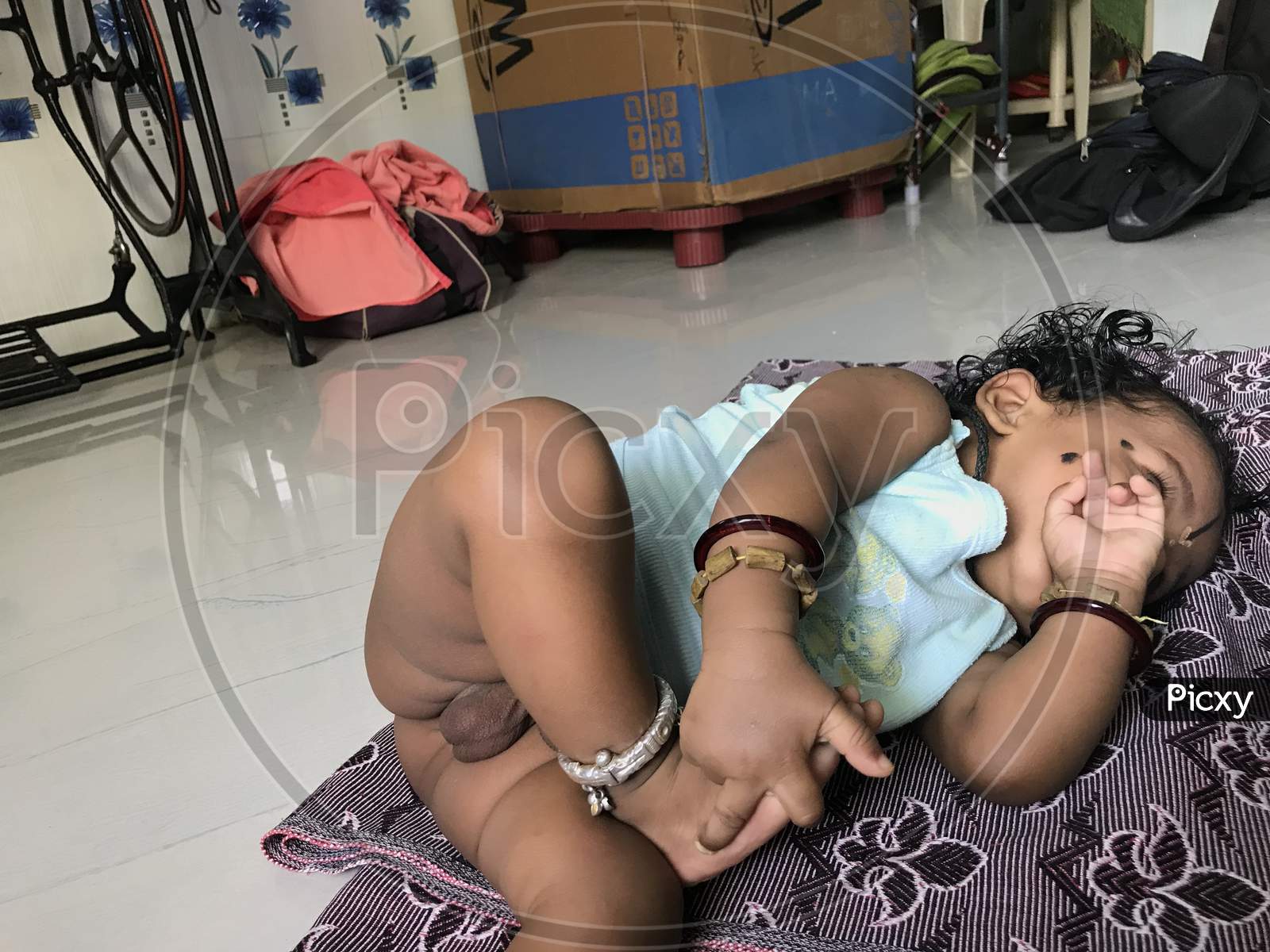 Image of 8 Months Old Indian Baby Boy Without Bottom Dress And Playing With  His Legs And Hands-ET015142-Picxy