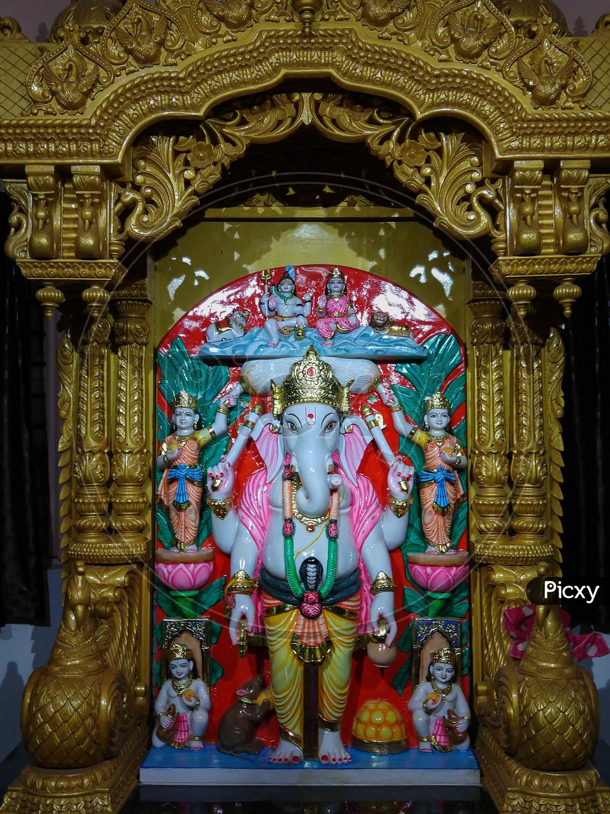 Lord Ganesha Statue In Standing Posture With A Decorated Wooden Background
