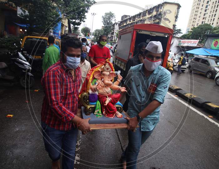 Devotees wearing masks carry home an idol of elephant-headed Hindu god Ganesha for worship during Ganesh Chaturthi festival celebrations in Mumbai, India, on August 22, 2020.
