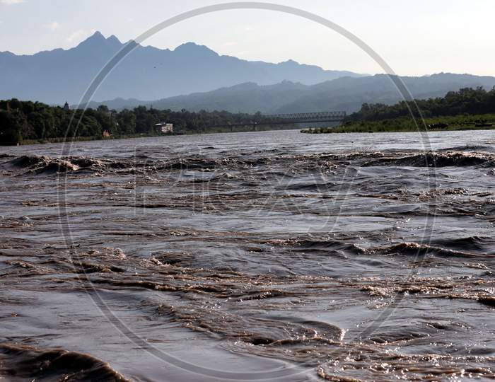 People watching river Chenab in full spate in Akhnoor area of Jammu on August 22, 2020 after authorities opened Salal Dam reservoir gates following heavy rains over the past two days in Jammu and Kashmir.